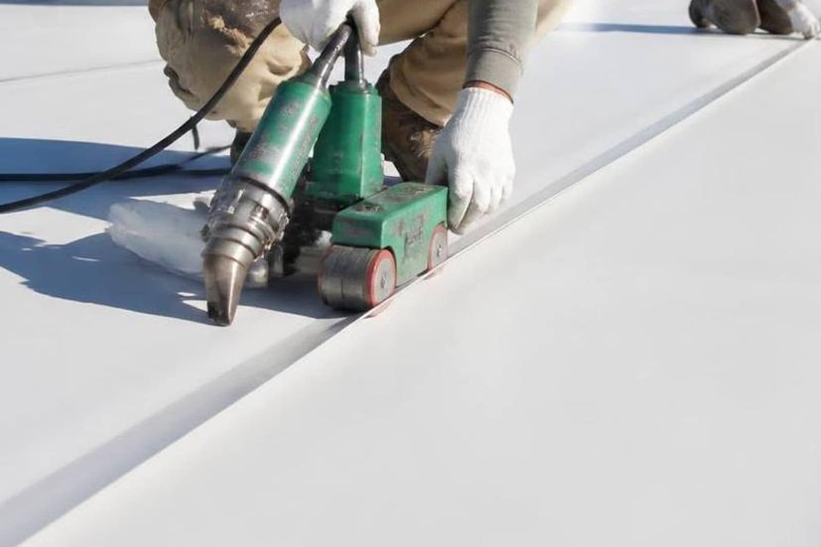 Hot-air seam welder and roller sealing a seam on a roof membrane